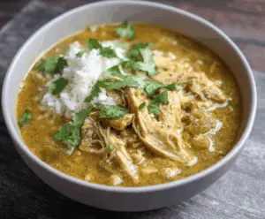 Delicious slow cooker chicken chili verde in a bowl garnished with fresh cilantro and lime, served with tortilla chips