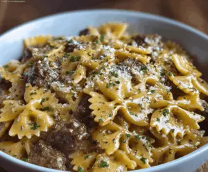Creamy Parmesan Garlic Beef Bowtie Pasta served in a white bowl, garnished with fresh herbs, showcasing a rich and flavorful pasta dish