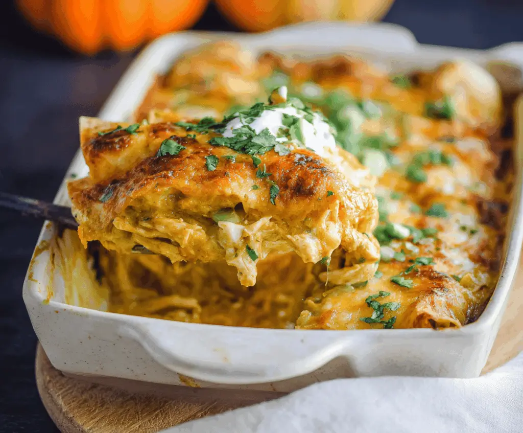Creamy Pumpkin Chicken Enchiladas topped with melted cheese and garnished with fresh cilantro on a rustic plate.