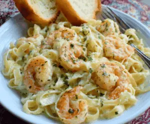 Creamy Olive Garden Shrimp Alfredo pasta dish garnished with herbs, served on a plate.
