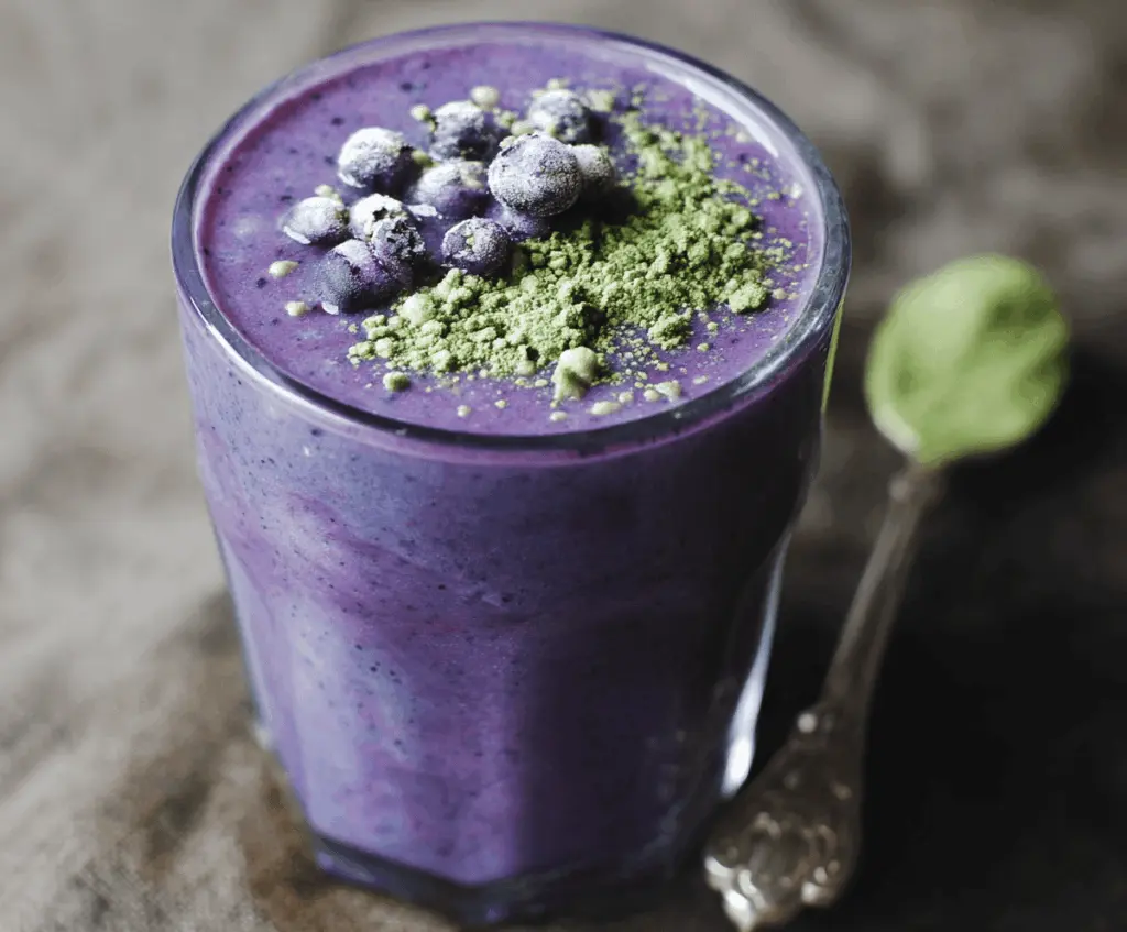 A vibrant glass of Wild Blueberry Vanilla Matcha Smoothie garnished with fresh blueberries and vanilla bean for a healthy breakfast.