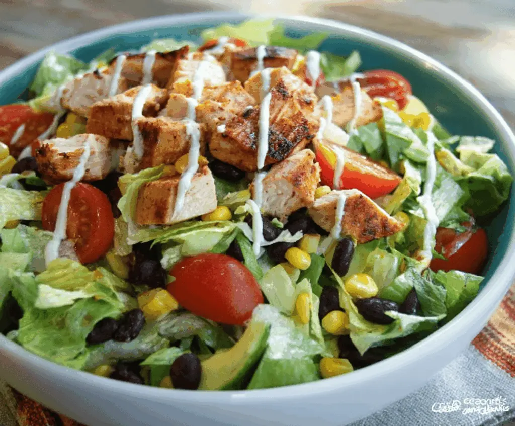 Colorful Zesty Southwest Chicken Salad with fresh lettuce, grilled chicken, corn, black beans, cherry tomatoes, and avocado slices on a vibrant plate