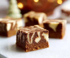Delicious Gingerbread Cheesecake Bars topped with spiced gingerbread crumble on a festive plate.