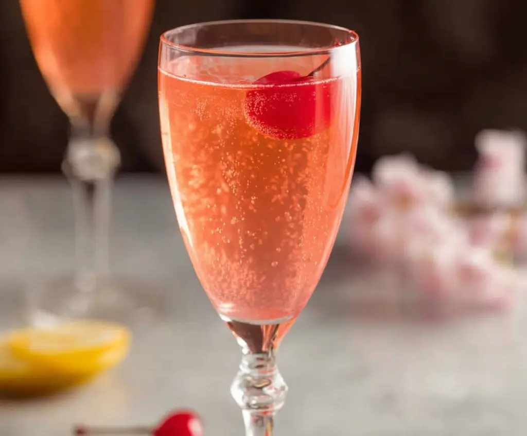Elegant Pink Champagne Cocktail garnished with a cherry in a tall flute glass