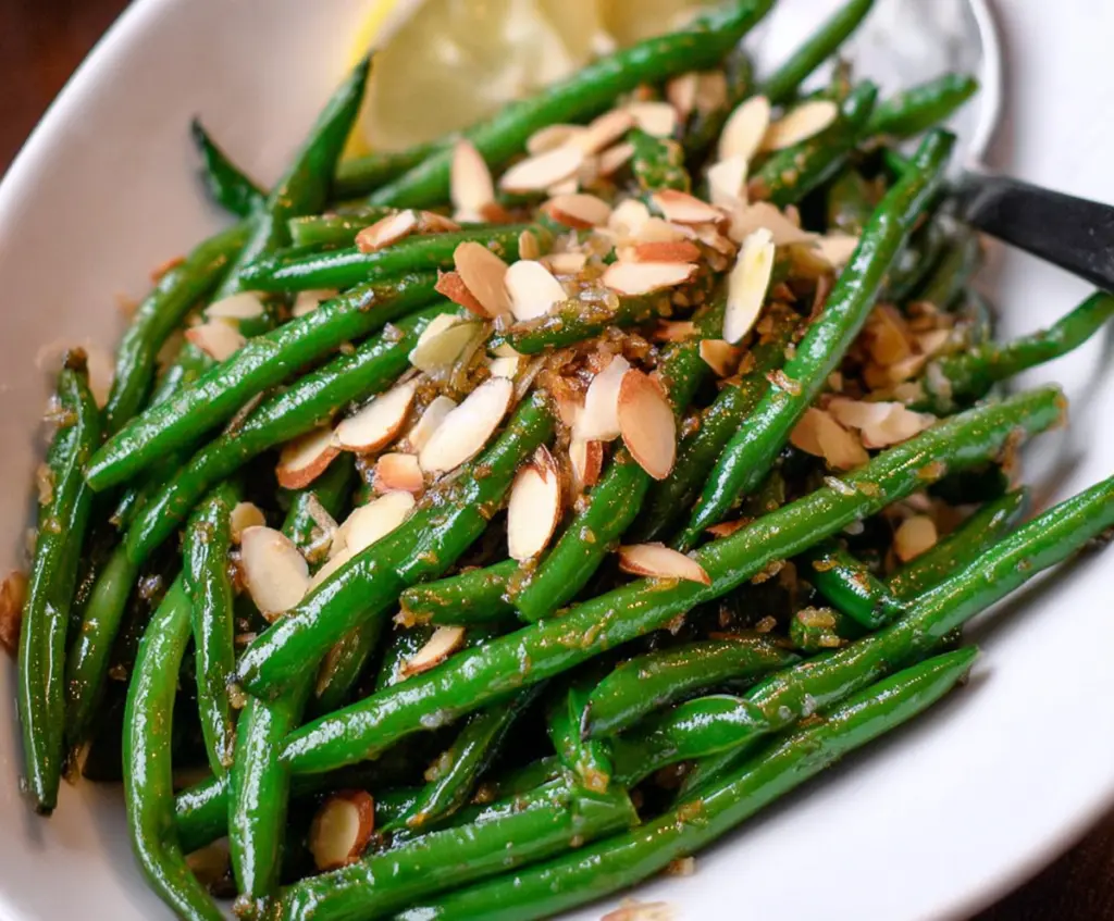 Delicious Green Bean Almondine with fresh green beans and toasted almonds on a white plate.